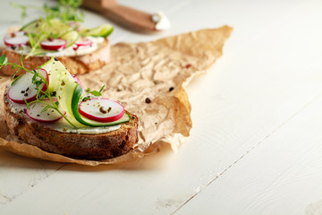 Sandwich with red radish, cucumber and fresh herbs and pepper.