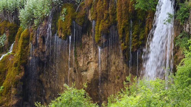 amazing waterfall in the forest cascades flows down from the cliff covered with moss