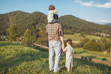 Happy father and son having fun and enjoying nature. Carpathian mountains. Sunny summer day. Happy family concept.