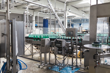 Industrial factory indoors and machinery. Robotic factory line for processing and bottling of pure spring water into canisters and bottles. Selective focus. Short depth of field.