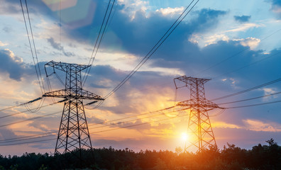 High-voltage power transmission towers in sunset sky background.