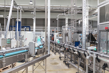 Industrial factory indoors and machinery. Robotic factory line for processing and bottling of pure spring water into canisters and bottles. Selective focus. Short depth of field.