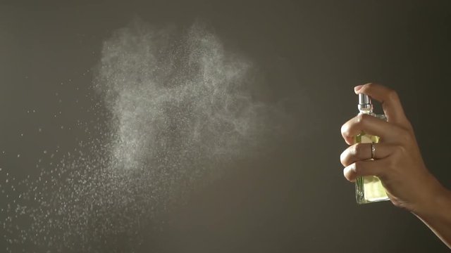 Slow motion,Woman spraying fragrance with scent particles.
