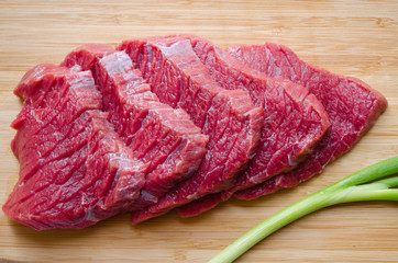 Fresh raw beef steak with  green onion on wooden table