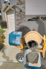 Yellow cement mixer pouring into wheelbarrow
