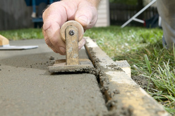 Close up of a man using edging tool on wet cement
