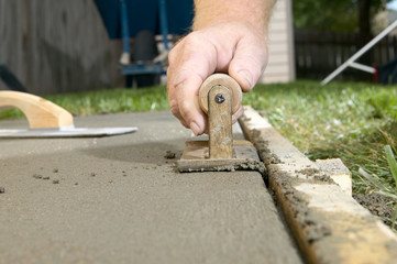 Close up of man finishing cement with edging tool