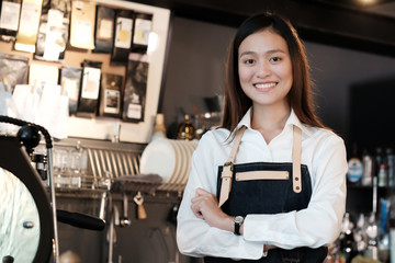 Fototapeta na wymiar Young asian women Barista standing with smiling face in font of cafe counter background, small business owner, food and drink industry concept