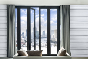 view of cityscape Bangkok skyline and river, Bangkok Thailand  from black Aluminum door with glass frame and wood wall in living room,  luxury resort