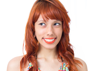 She looks to the side and gives a generous smile. Redhead girl wears colorful and cheerful dress....
