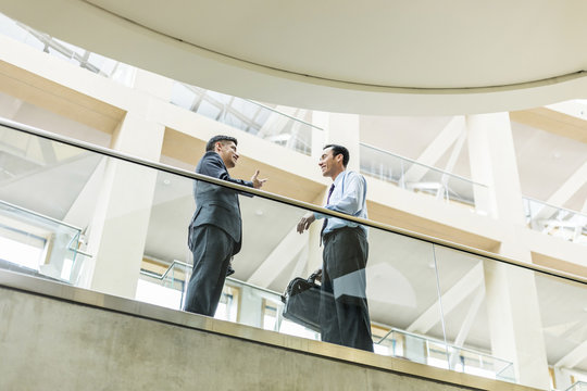 Smiling Mixed Race businessmen talking in lobby