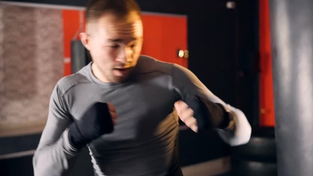 A man pretends to punch a heavy bag. 