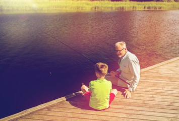 grandfather and grandson fishing on river berth