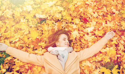 beautiful happy woman lying on autumn leaves
