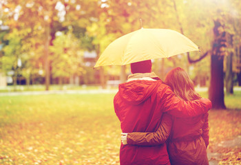 happy couple with umbrella walking in autumn park