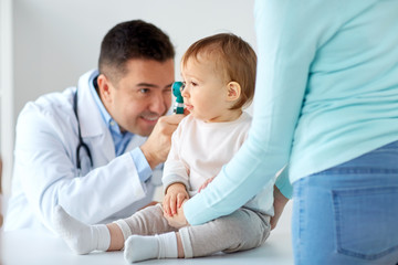 doctor with otoscope checking baby ear at clinic