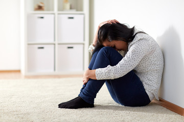 unhappy woman crying on floor at home - obrazy, fototapety, plakaty