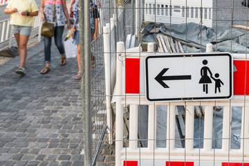 Baustelle mit Hinweisschild für Fußgänger und mit Fußgänger