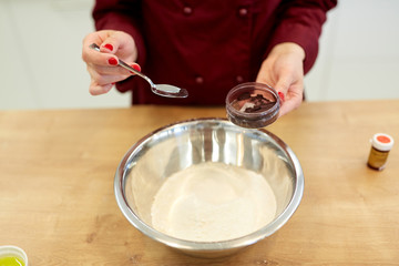 chef hands adding food color into bowl with flour