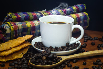 A cup of coffee on an old kitchen table and dessert.