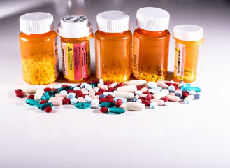 Five pill bottles with pile of pills