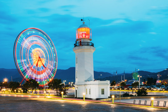 Batumi, Adjara, Georgia. Ferris Wheel In Motion And Pitsunda Lighthouse At Promenade In Miracle Park
