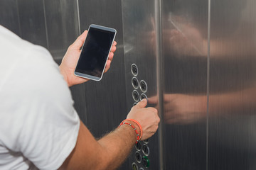 Man holding smartphone in elevator