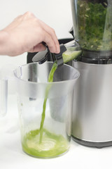 Cold press juicer with squeezed juice. Green detox juice in cold extraction blender