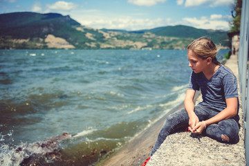 Sad little girl sitting by the water