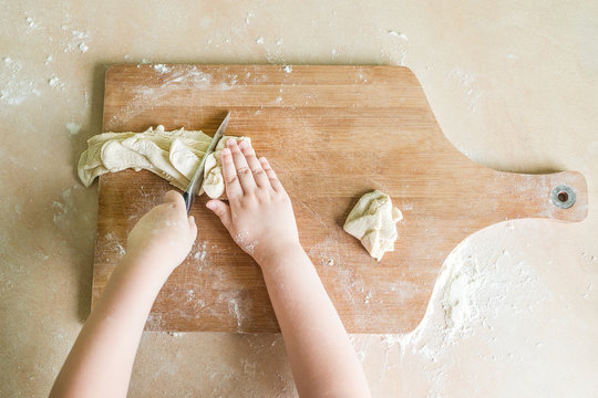 children's hands cutting raw dough