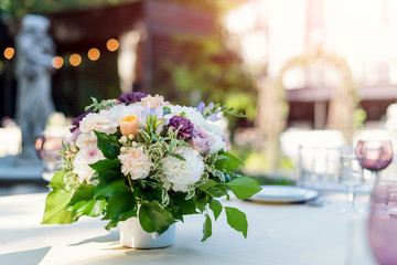 Flower table decorations for holidays and wedding dinner. Table set for holiday, event, party or wedding reception in outdoor restaurant.