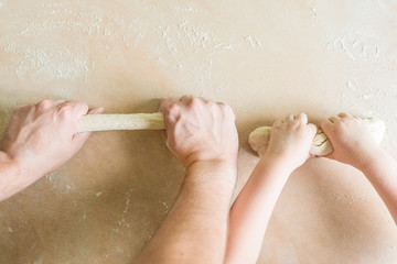 Fototapeta premium Children's and dad's hands makes raw dough