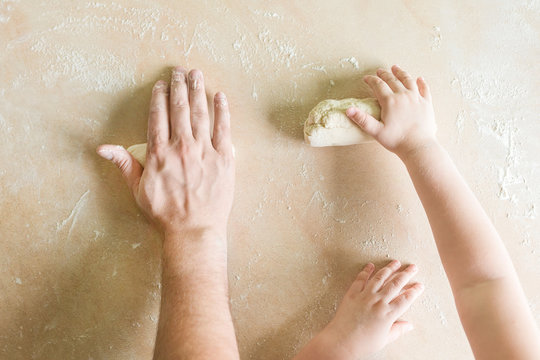 Children's and dad's hands makes raw dough