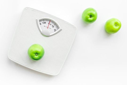 Bathroom scale and apples on white background top view copyspace