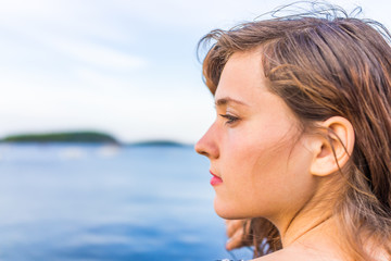 Profile portrait of young happy smiling woman sitting on edge of dock in Bar Harbor, Maine looking...
