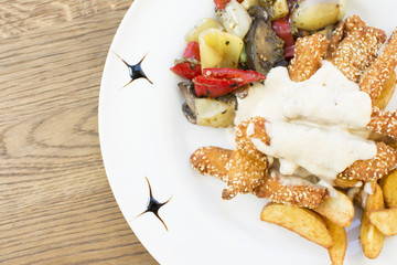 Delicious sesame chicken sticks with potatoes and vegetables. Delicious buttery topping. Beautifully served plate at the restaurant.