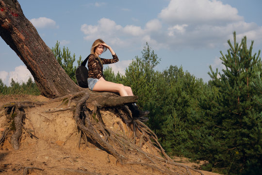 Attractive tourist girl sitting on root of tree and taking rest after walk © boomeart