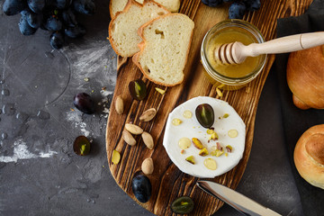 Cheese with white mold. Camembert or brie type. Grape, honey, bread, pistachios. Healthy breakfast.