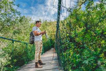 Hiker using smart phone on the wooden suspension bridge