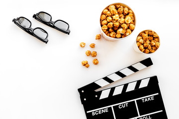 To go to the cinema. Clapperboard, glasses and popcorn on white background top view copyspace