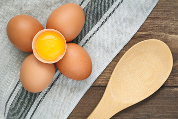 Top view on fresh eggs on a linen towel and wooden big spoon. Cooking concept.