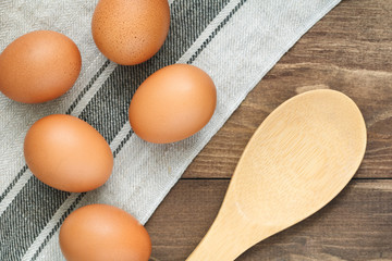 Top view on fresh eggs on a linen towel and wooden big spoon. Cooking concept.