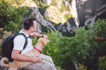 Hiker and his dog sitting on the mountain top