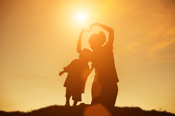 Mother encouraged her daughter out of the shadows at sunset.