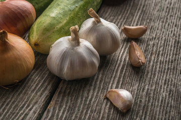 Garlic, onion, cucumber, potatoes and tomato on an old table