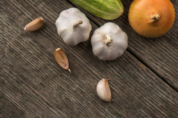 Garlic, onion, cucumber, potatoes and tomato on an old table