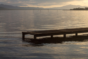 A pier on a lake at sunset, with beautiful soft and warm colors