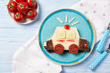 Funny sandwich with cheese and vegetables in a shape of police car, meal for kids idea, top view