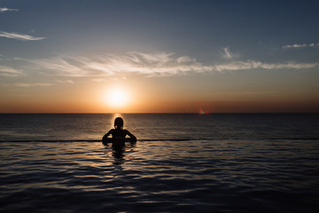 Fototapeta na wymiar silhouette of a girl in the pool, rolling in the sea