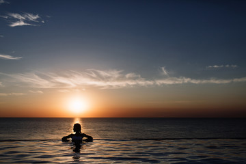 Naklejka na ściany i meble silhouette of a girl in the pool, rolling in the sea